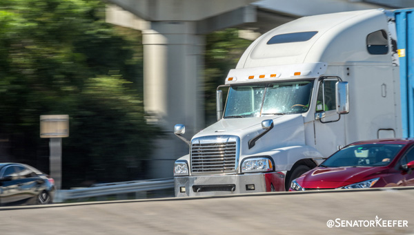 White tractor trailer driving on the road.