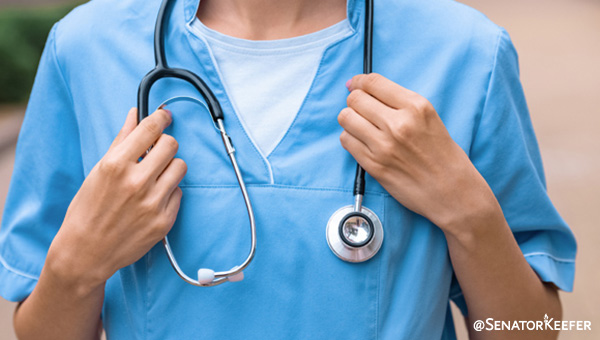 A medical person wearing a blue uniform with a stethoscope around their neck.