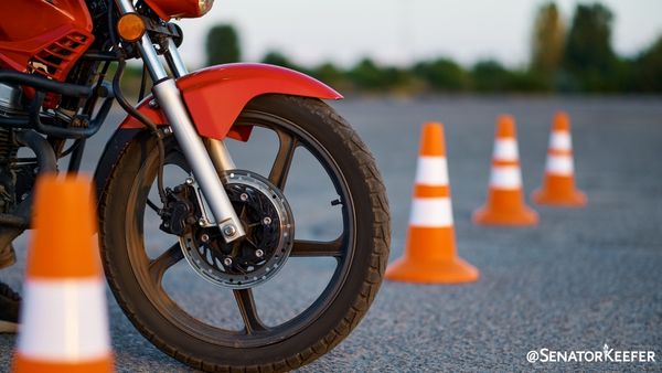 Blacktop road with small construction cones and a motorcycle.