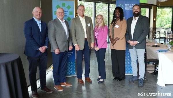 Senator Dawn Keefer and other York County leaders stand in an open room in front of a York County Economic Alliance banner.