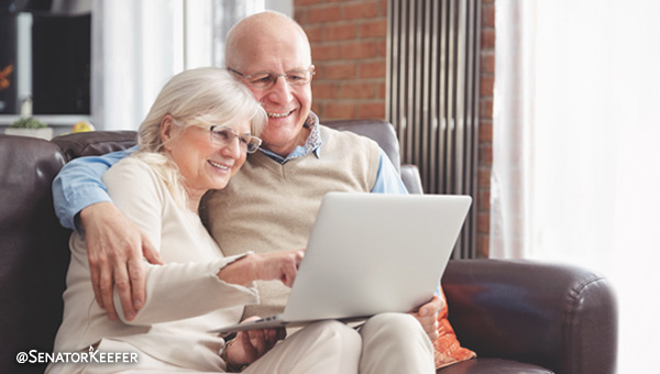 A man and women on a couch looking at a laptop.