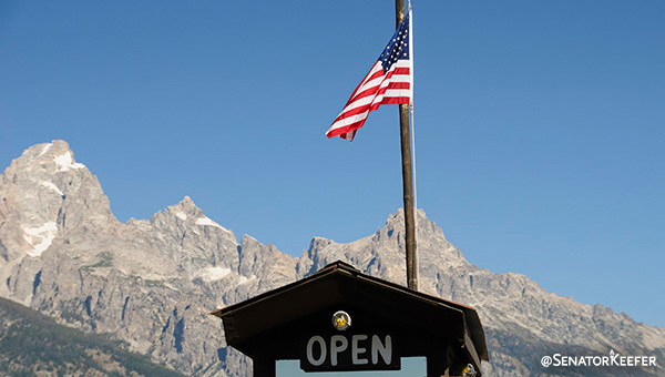 Mountains in the background of a building with an American flag flying above it.