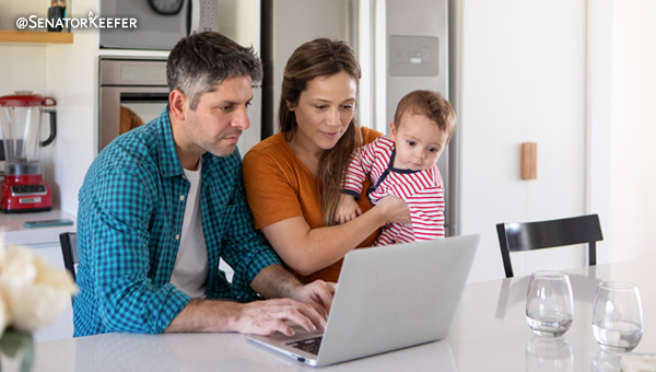 A young family looking at a laptop on a kitchen counter.