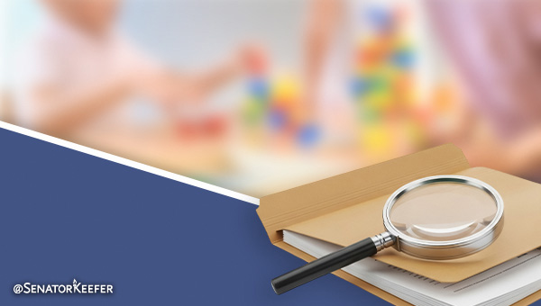 magnifying glass on a book with blurred image of child playing in the background.