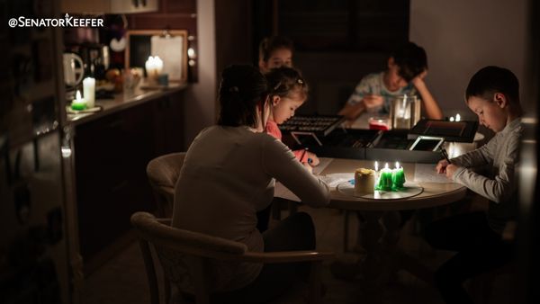 Family sitting around table in the dark with candles for light.