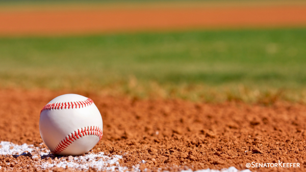 A close-up of a baseball laying on a baseball field.