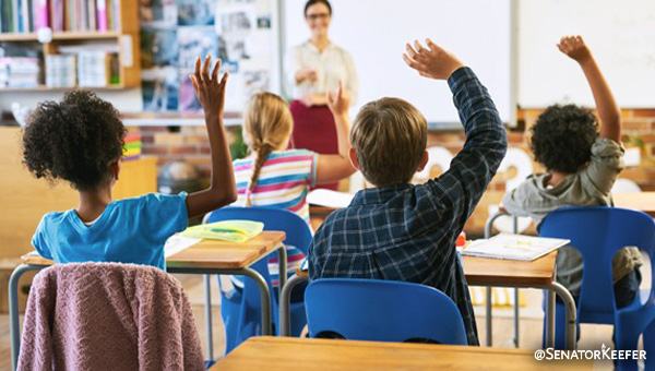 Classroom with student’s hands raised.