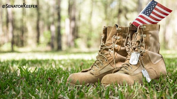 military boots sitting in grass with dog tags and an American flag.