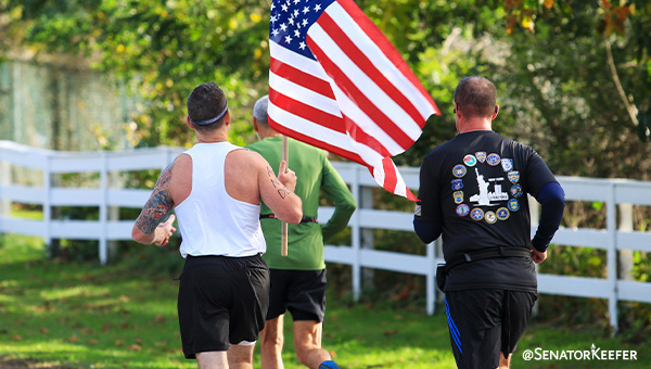 Three men running with one holding an American flag.