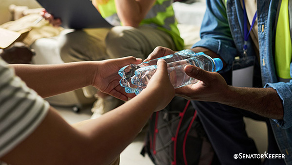 a person handing two water bottles to another person.