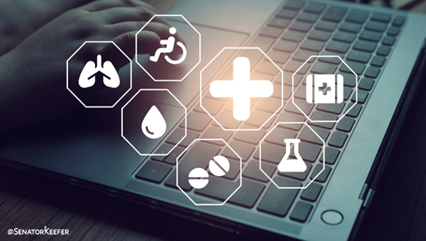 Close-up of a laptop keyboard with a hand resting near it, overlaid with glowing medical icons including a cross, lungs, heart, blood drop, medication, and laboratory flask.