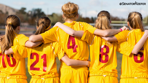 A picture of girls standing in a row with their arms around each other’s backs.