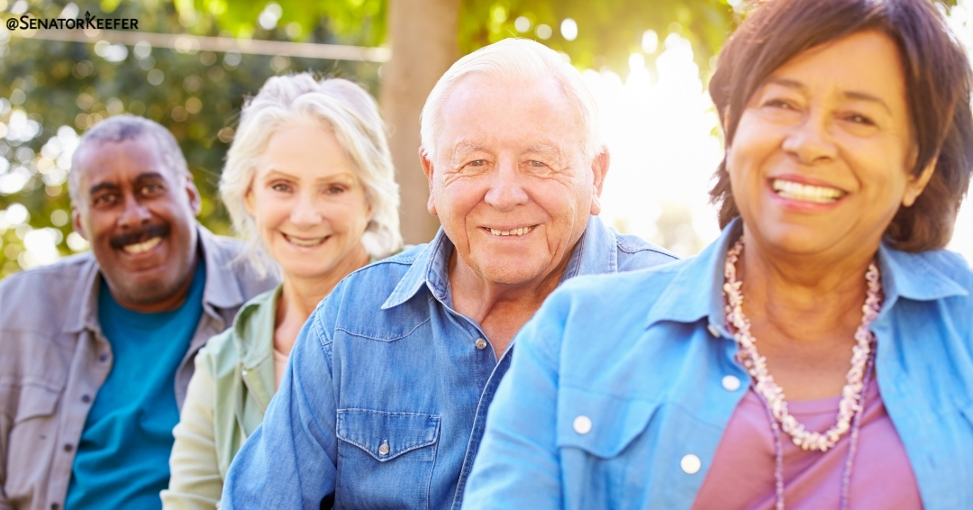 A group of four smiling adults sitting outdoors.